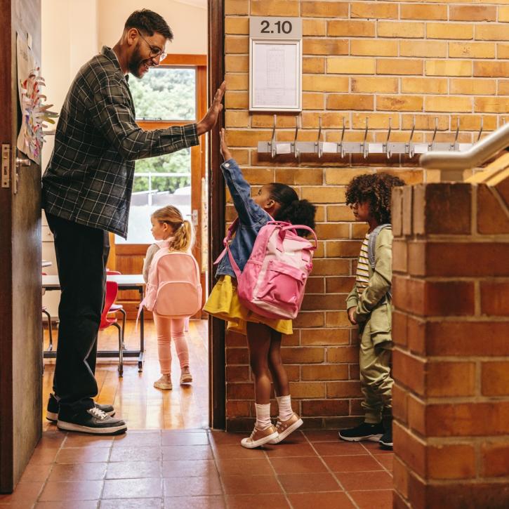 kleuters lopen klas binnen en geven high five met meester