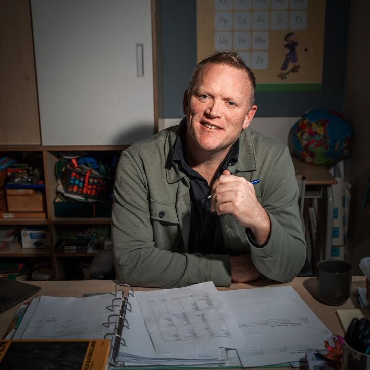 Thijs Roovers poseert aan zijn bureau in de klas