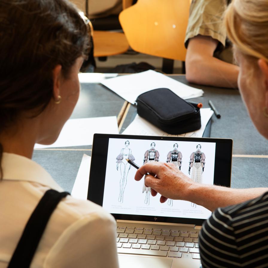 Twee personen kijken naar een tekening op een laptopscherm