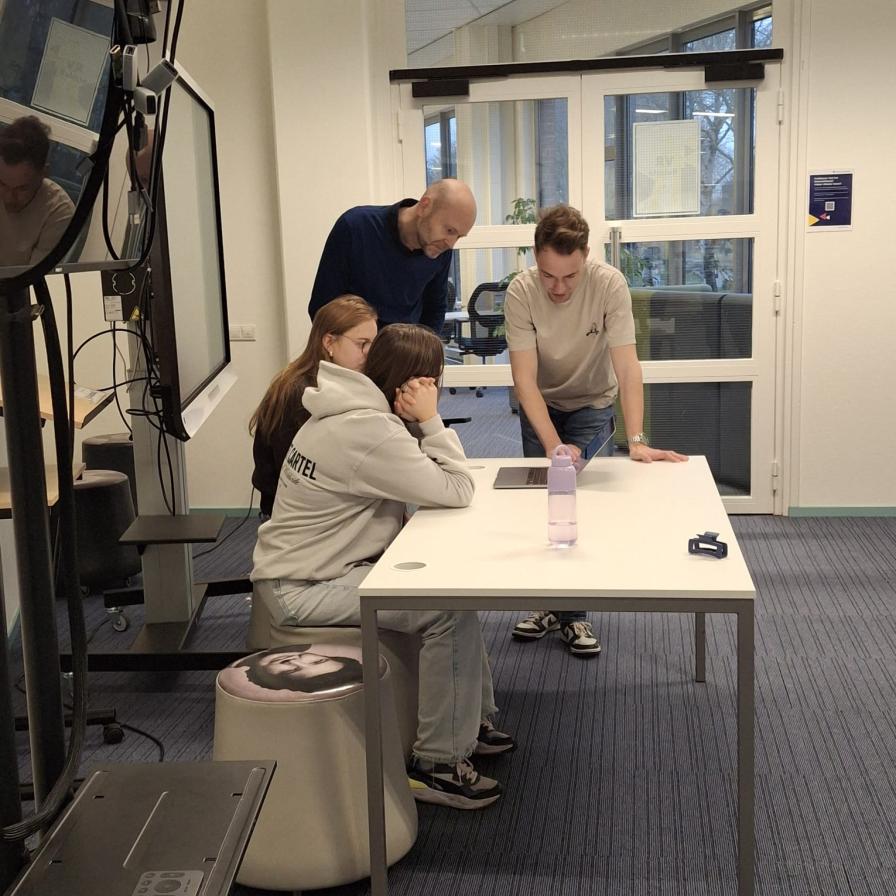 Docent en studenten bij laptop