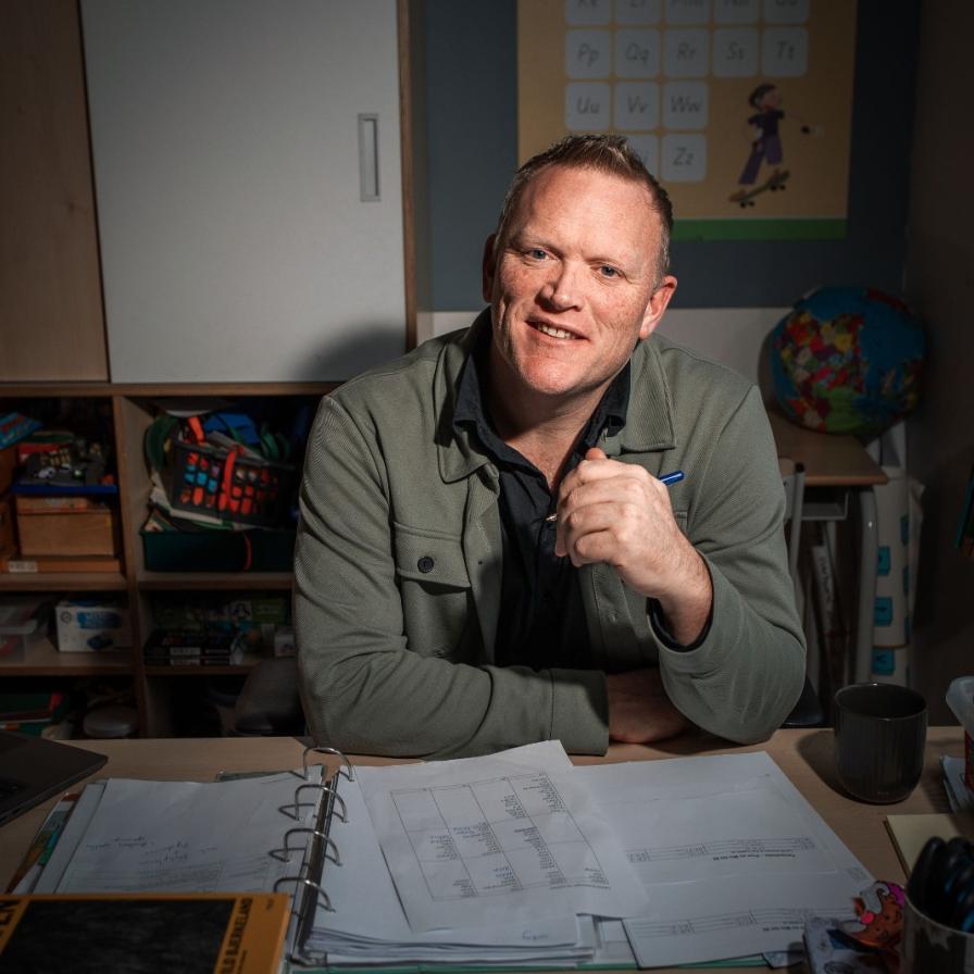 Thijs Roovers poseert aan zijn bureau in de klas