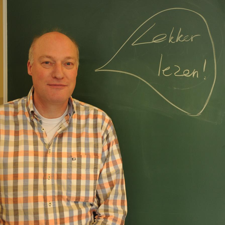 docent staat voor het schoolbord met daarop geschreven lekker lezen