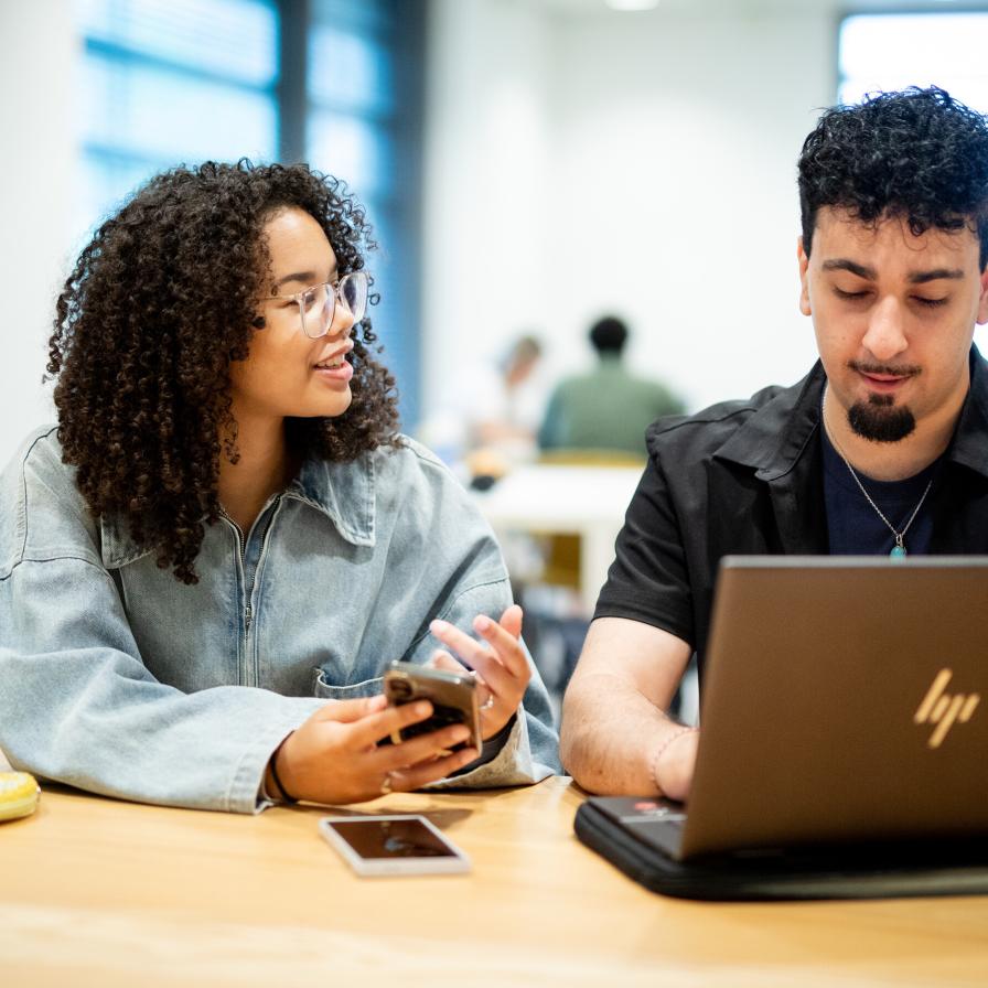 Twee studenten werken samen achter een laptop