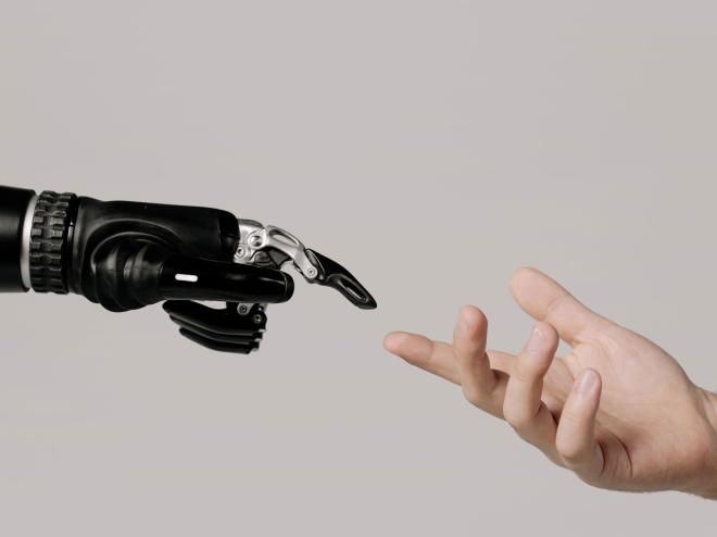 Menselijke hand reikt naar robotarm; verbeelding van verantwoorde samenwerking tussen mens en AI bij het HvA-lectoraat Responsible IT.